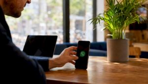 Persona sosteniendo un móvil en la mano con la aplicación de WhatsApp cerrada