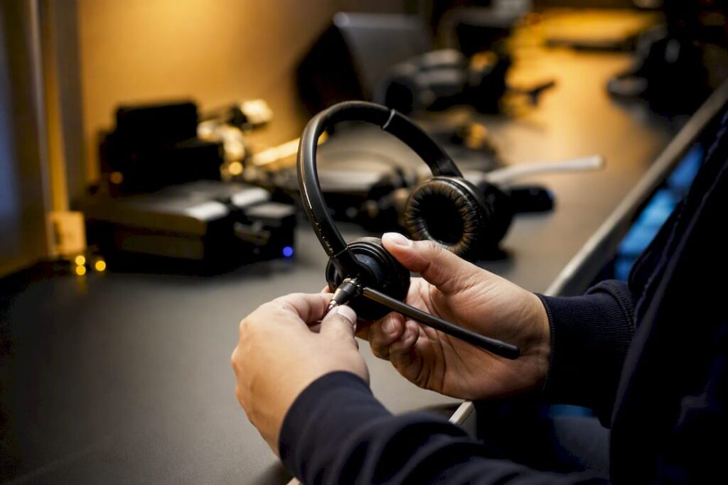 Manos ajustando el micrófono de un auricular telefónico