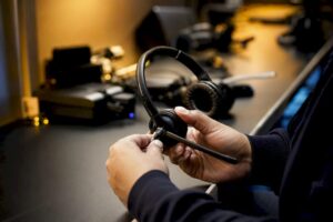 Manos ajustando el micrófono de un auricular telefónico