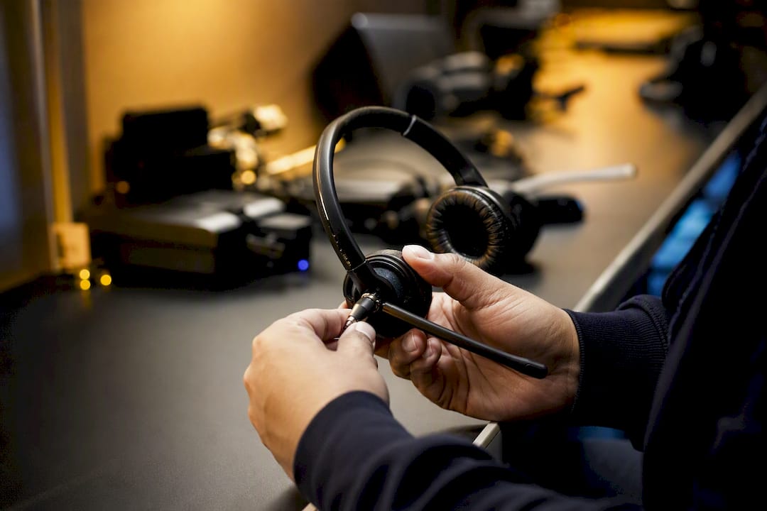 Manos ajustando el micrófono de un auricular telefónico