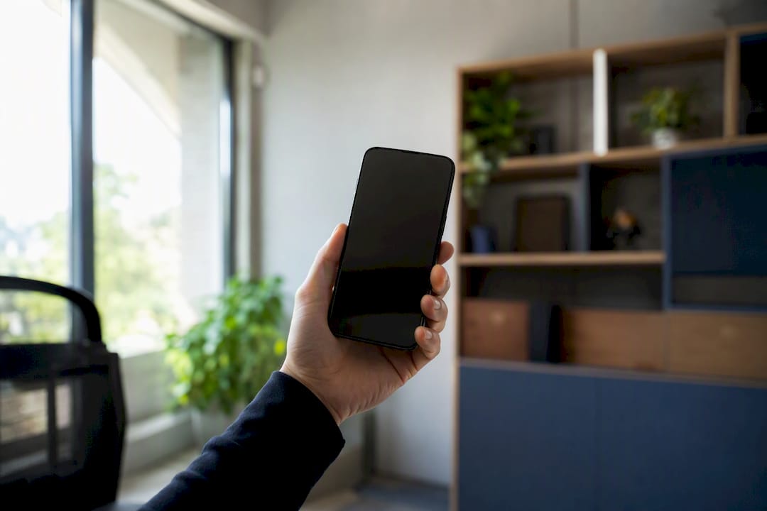 Mano sosteniendo un smartphone mientras prueba un asistente de inteligencia artificial